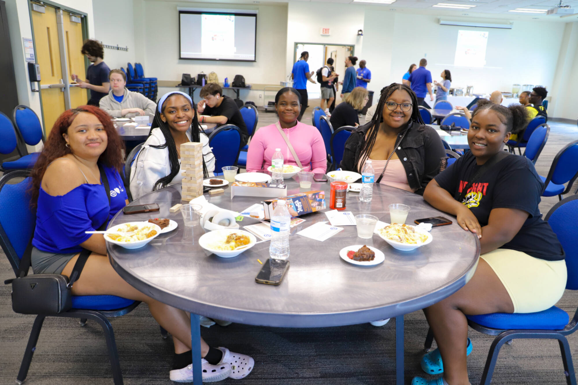 Students sitting around a table with board games, letter envelops, and food